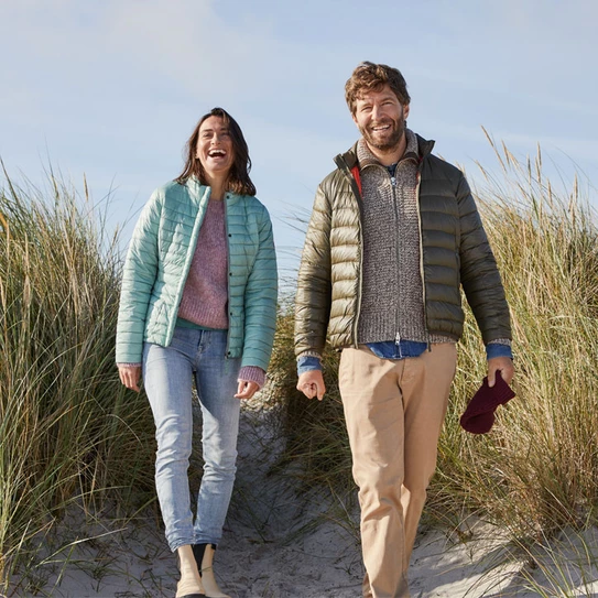 Lächelndes Paar geht durch Dünen am Strand